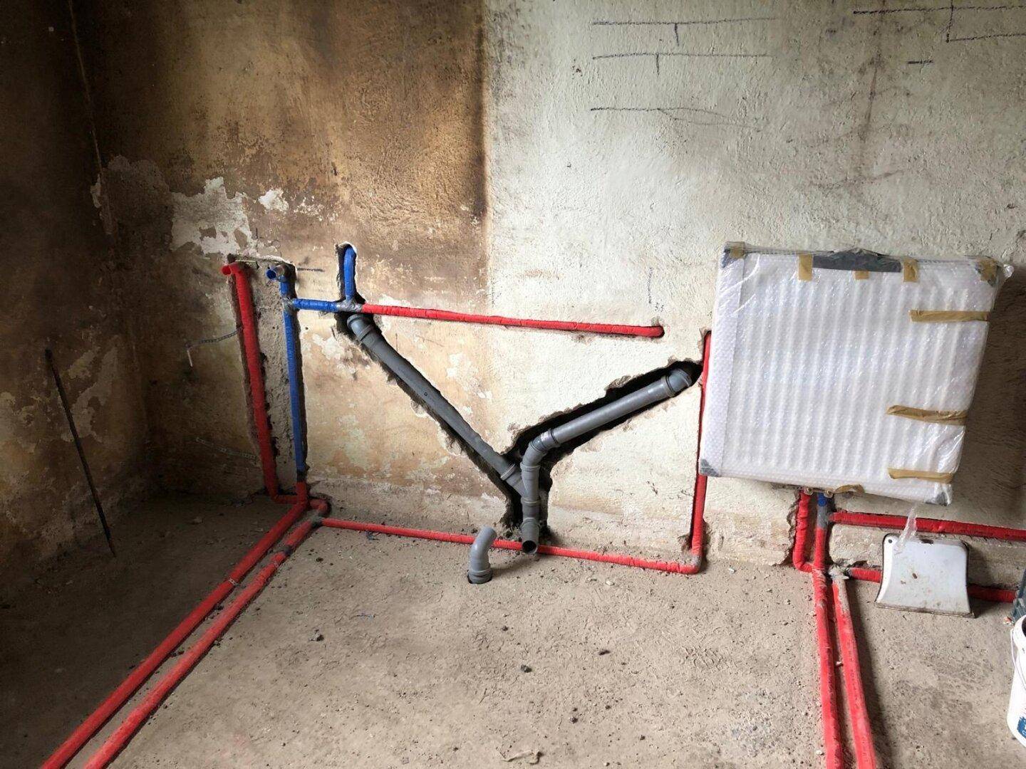 Sichtbare Wasser- und Abwasserleitungen im Rohbau eines Badezimmers, bereit für den Ausbau.