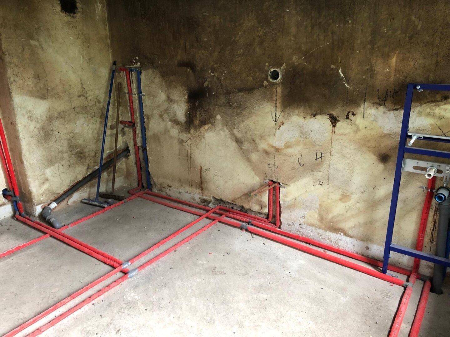 Umfassende Rohrinstallationen für Wasser und Heizung in einem Raum, der auf den Ausbau wartet.