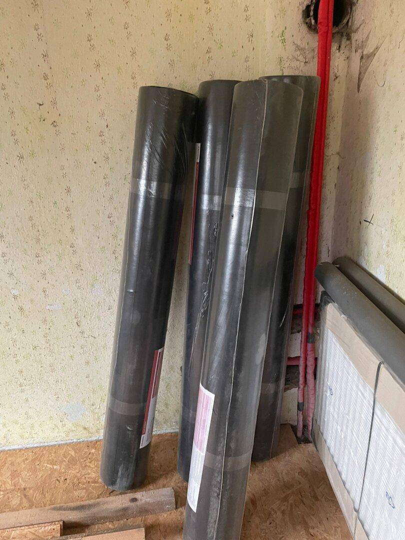 Lagerraum mit Baumaterialien, Rohren und einem verpackten Heizkörper, bereit für den Einbau.