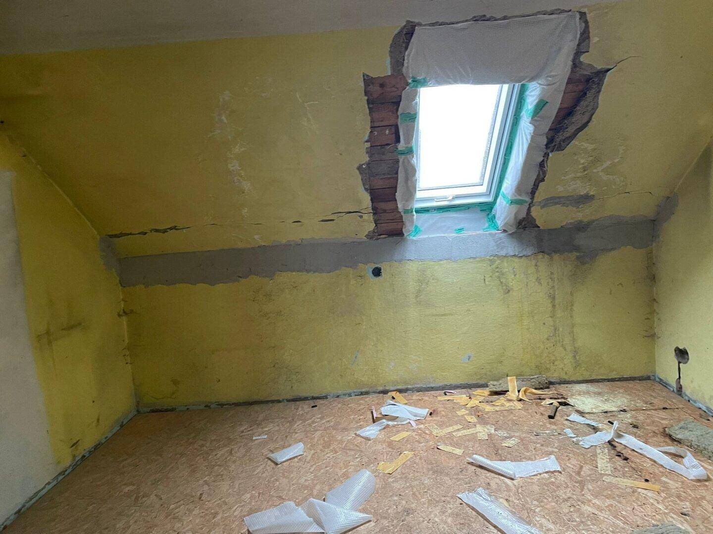 Dachgeschossraum in Renovierung mit Dachfenster und Spuren alter Wandfarbe.