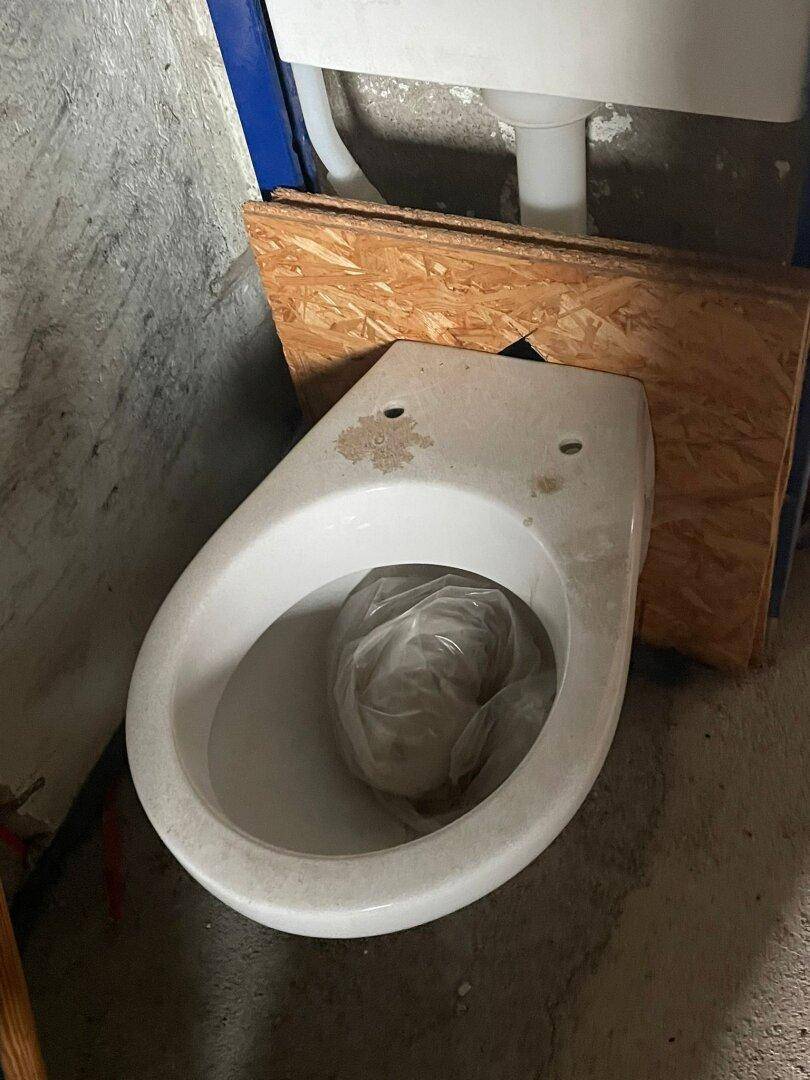 Neue Toilettenschüssel auf dem Boden, bereit für die Installation im Badezimmer.