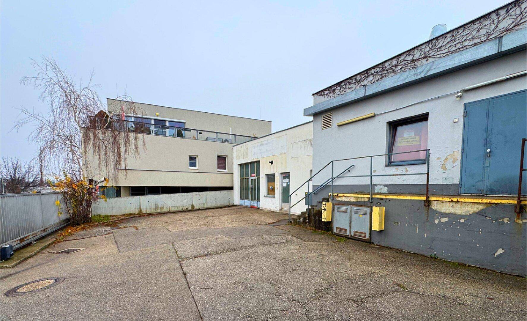 Hinterhofbereich mit asphaltiertem Parkplatz und angrenzenden Gebäuden.