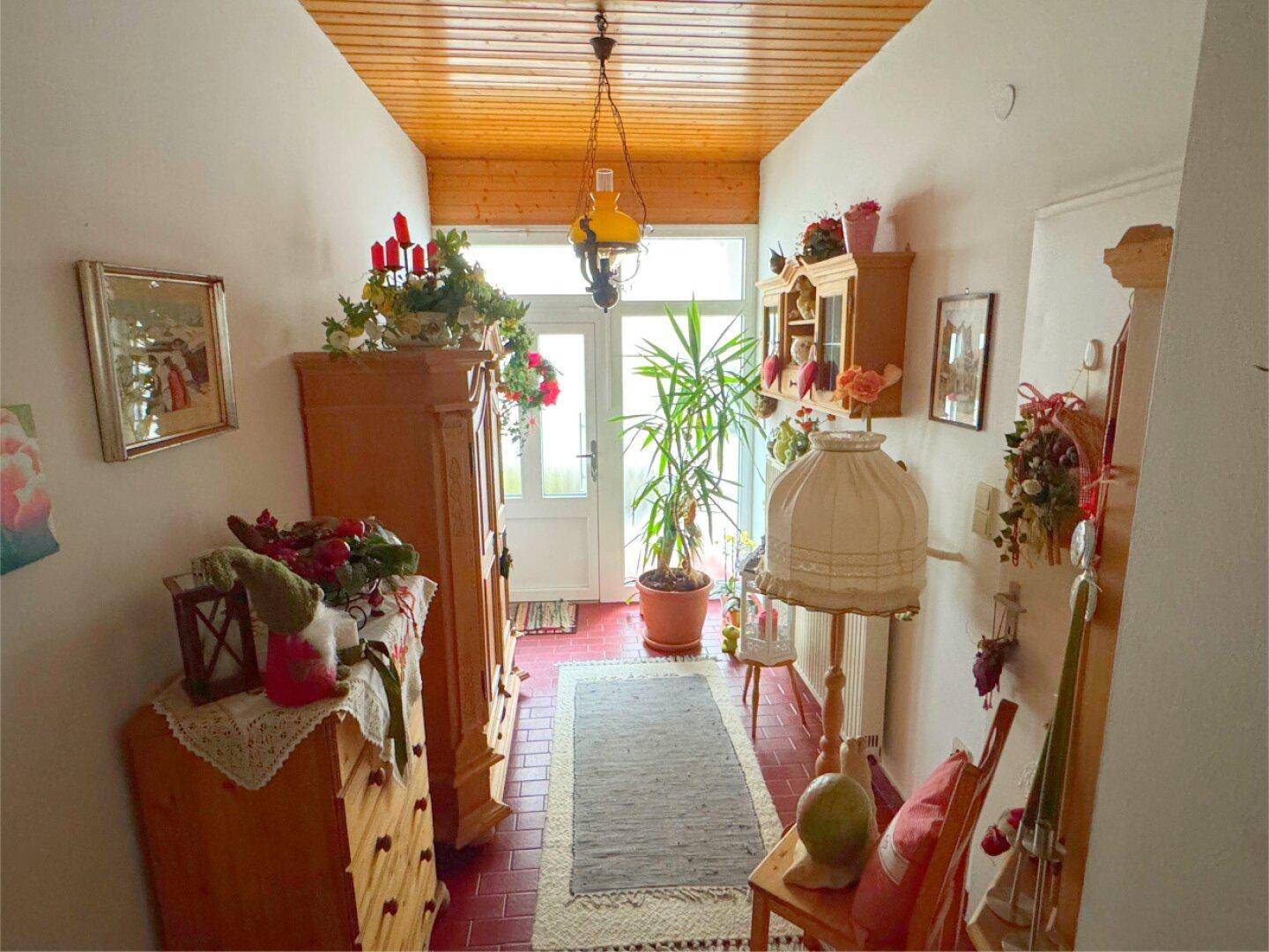 Gemütlicher Eingangsbereich mit Holzdecke, Terrakottaboden und traditioneller Dekoration.