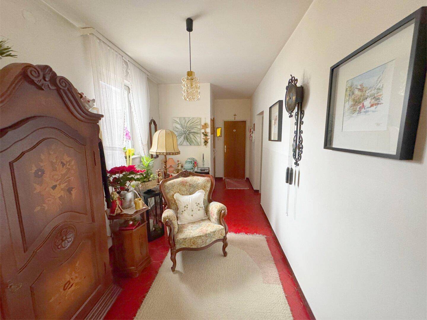 Langer Flur mit Terrakottaboden, einem Sessel und traditionellen Dekorationselementen.