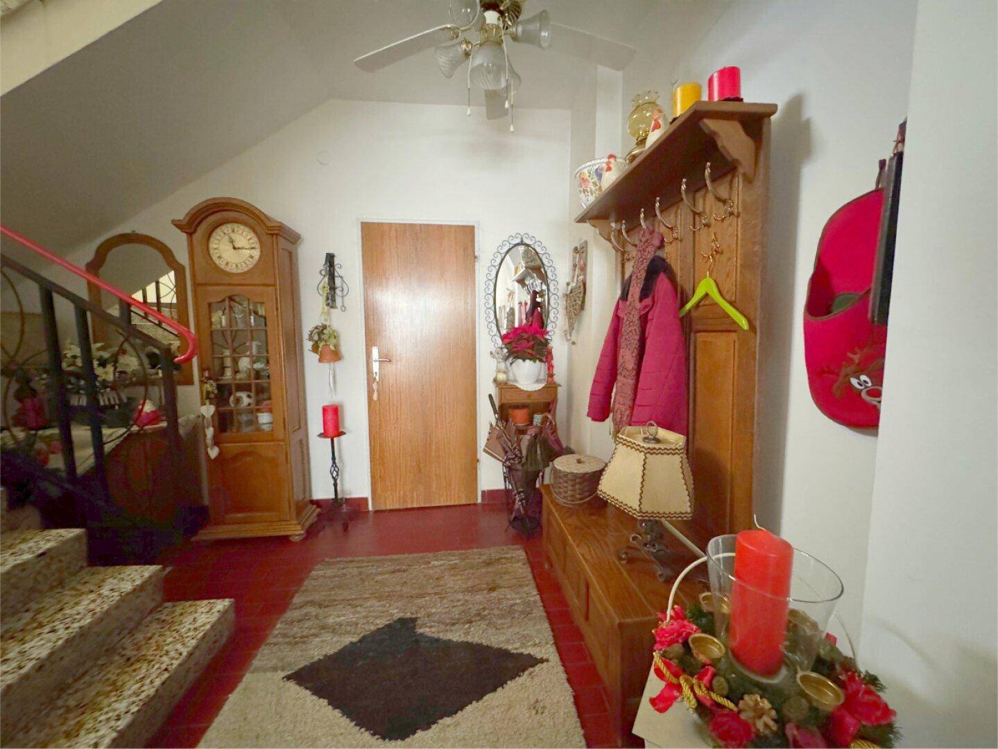 Flur mit Terrakottaboden, Holzmöbeln und einer Treppe zum Obergeschoss.