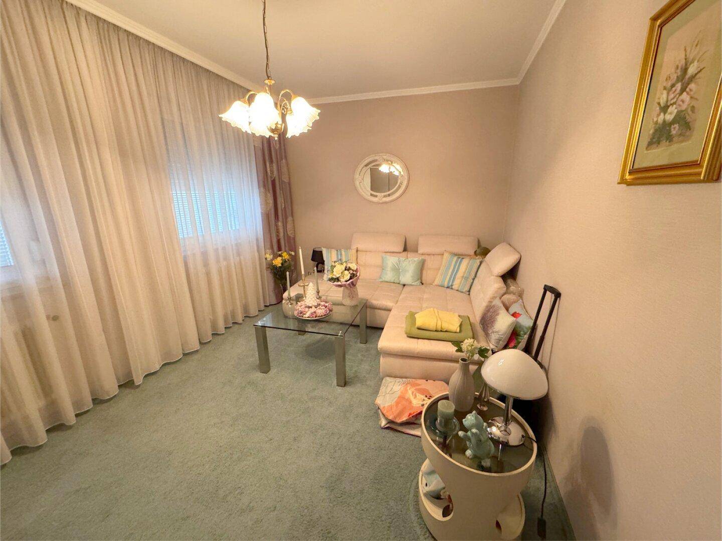 Gemütliches Wohnzimmer mit Teppichboden, Ecksofa und Couchtisch.