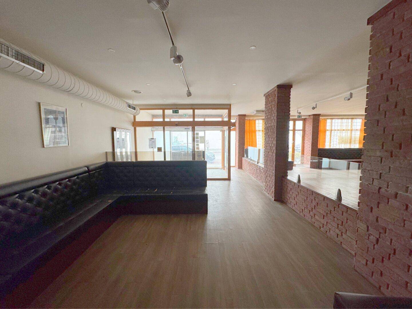 Geräumiger Eingangsbereich mit Holzboden, Sitzbänken und großen Glastüren.