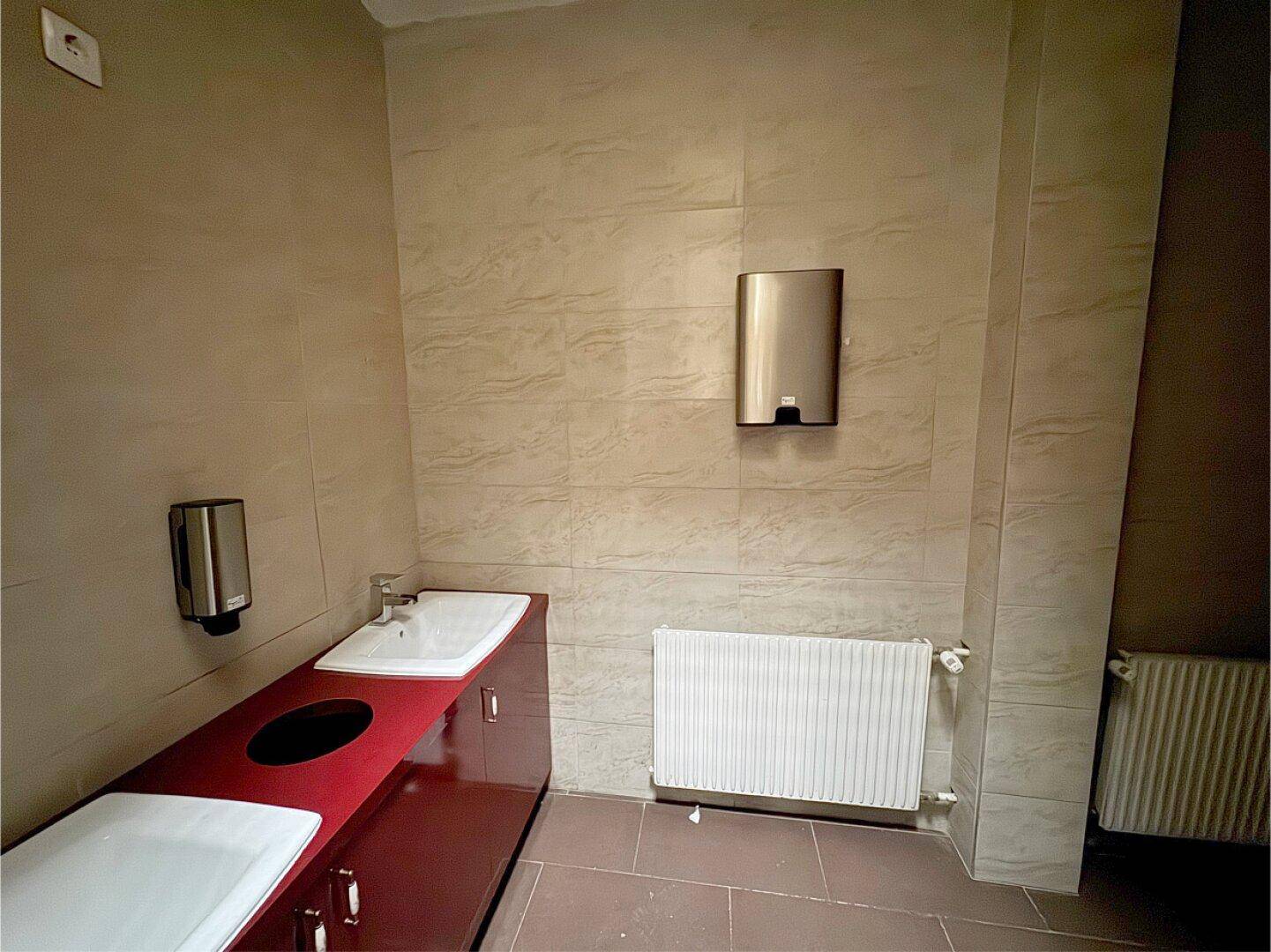 Sanitärbereich mit gefliesten Wänden, zwei Waschbecken und Heizkörper.