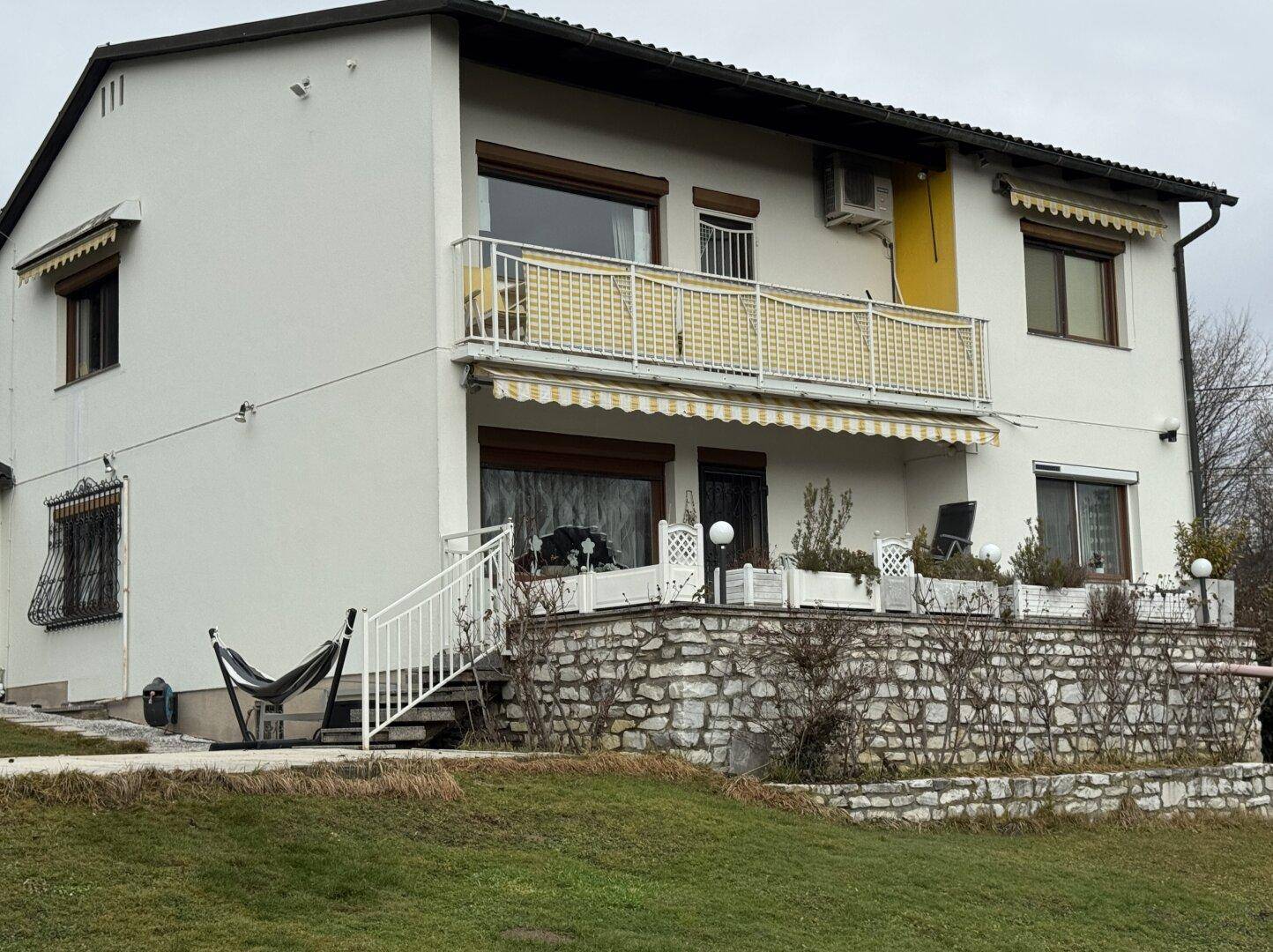 Die Hausfassade mit einer möblierten Terrasse und einem Balkon mit Markise.