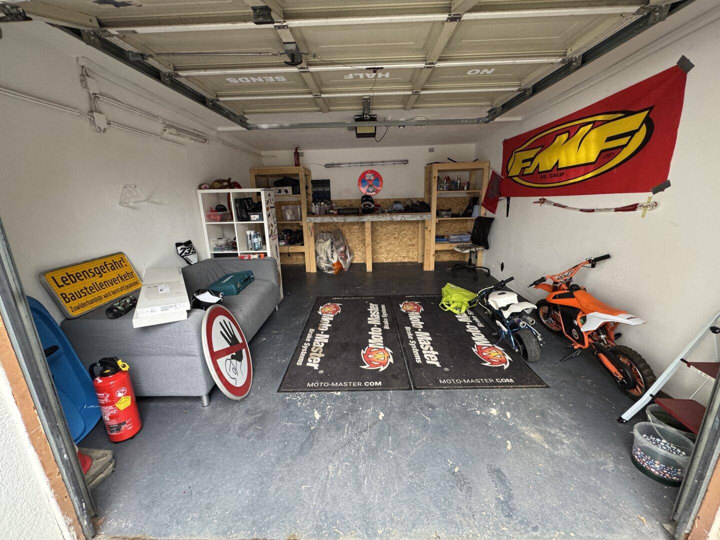 Geräumige Garage, die als Werkstatt und Abstellraum für Motorräder genutzt wird.