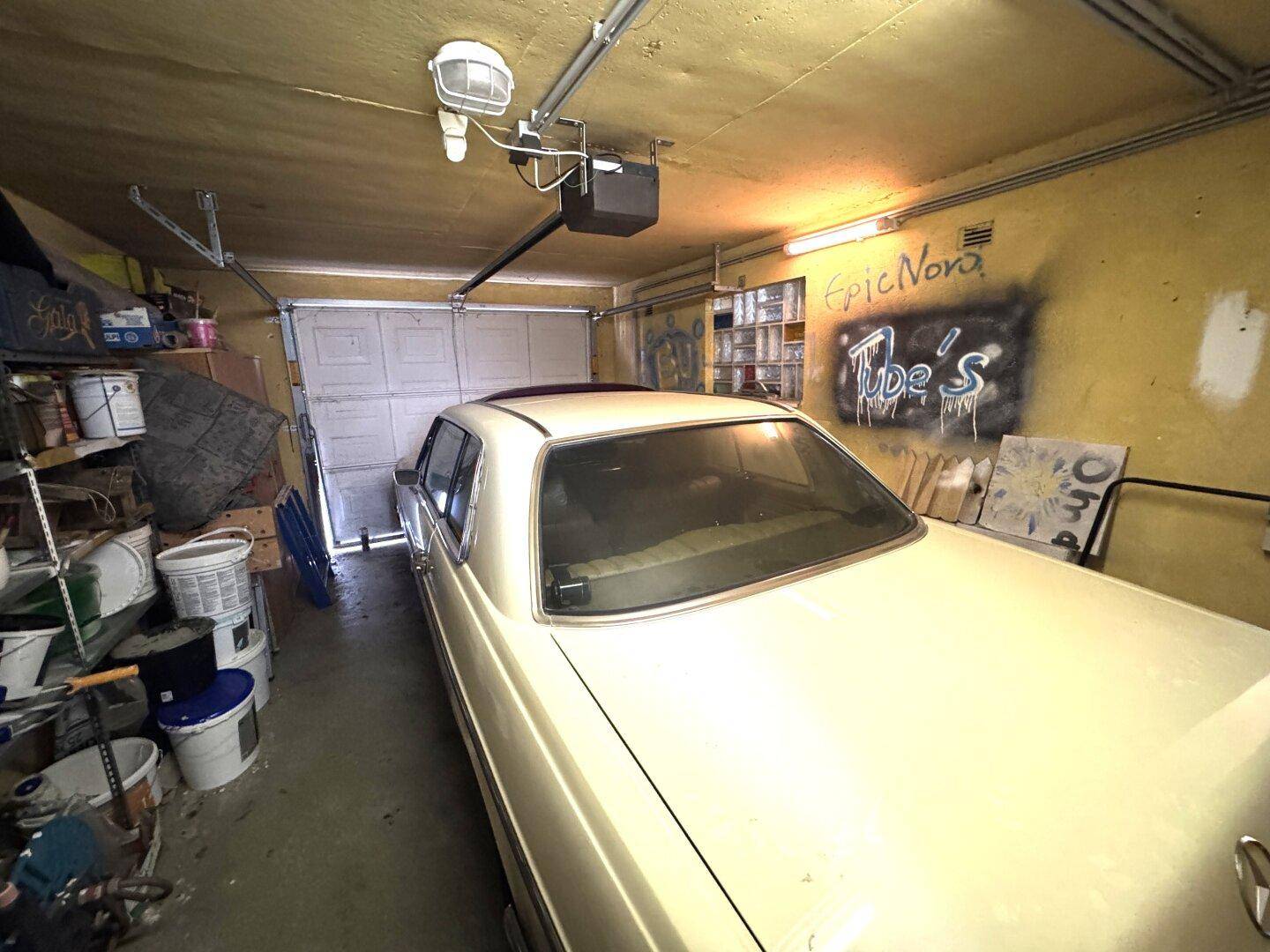 Garage mit einem Oldtimer, Regalen und verschiedenen Lagergegenständen.