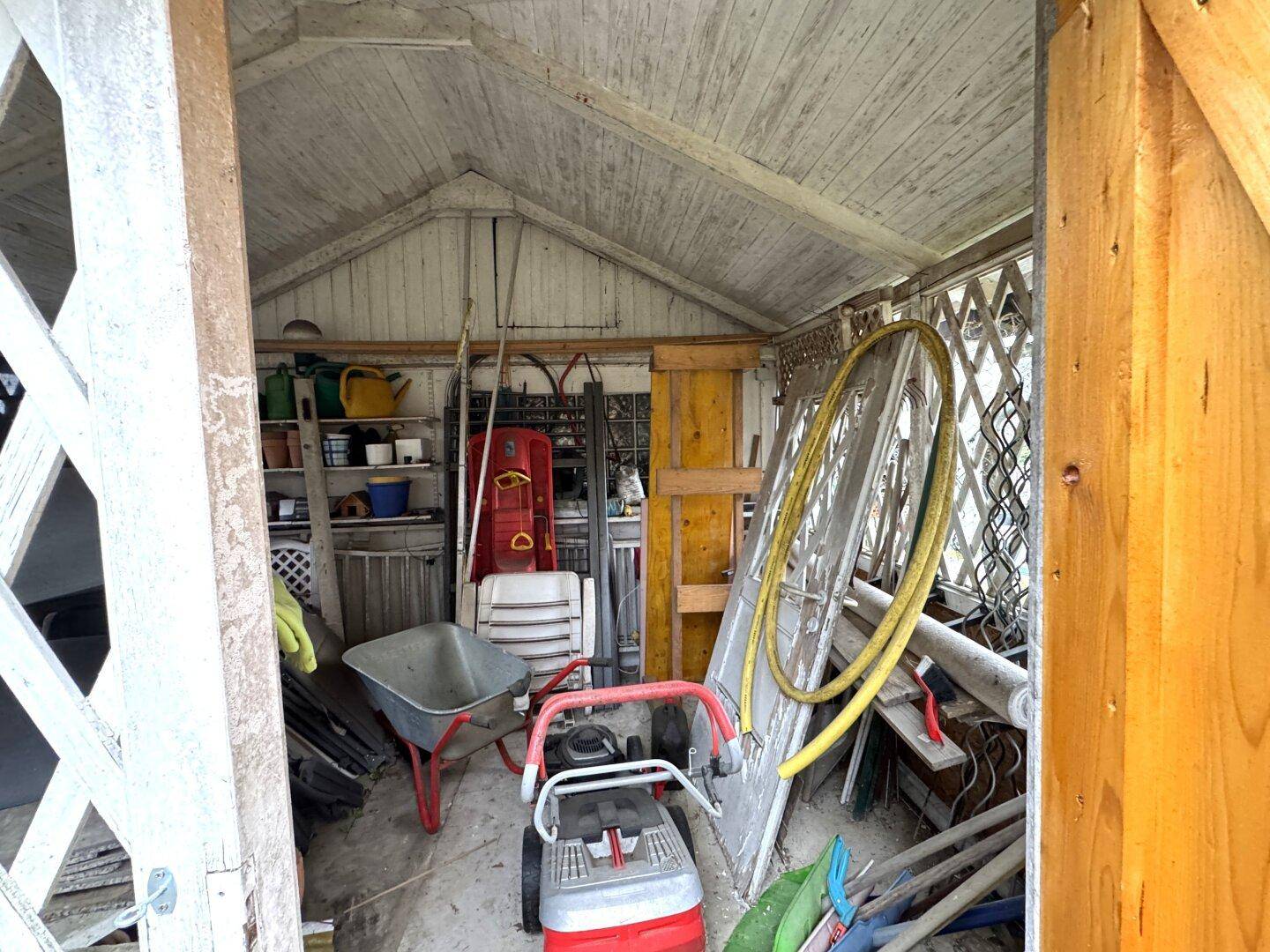 Innenansicht des Holzschuppens mit Gartengeräten und verschiedenen Utensilien.