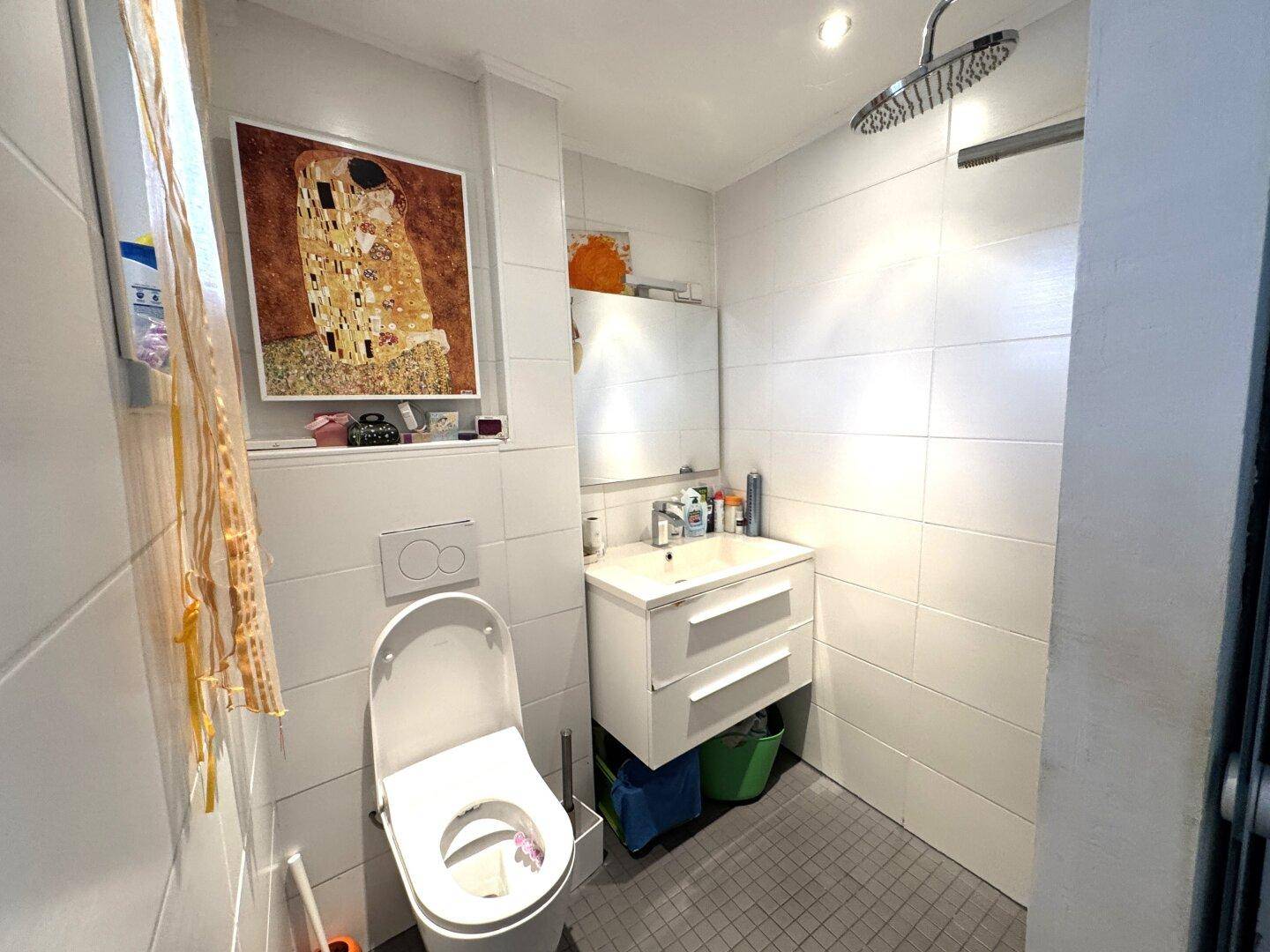 Modernes Badezimmer mit weiß gefliesten Wänden, Regendusche und wandhängendem WC.