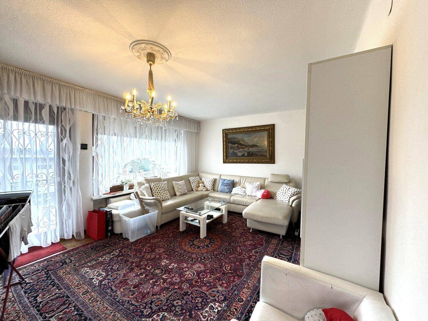 Gemütliches Wohnzimmer mit großem Ecksofa, Teppich und Zugang zum Balkon.