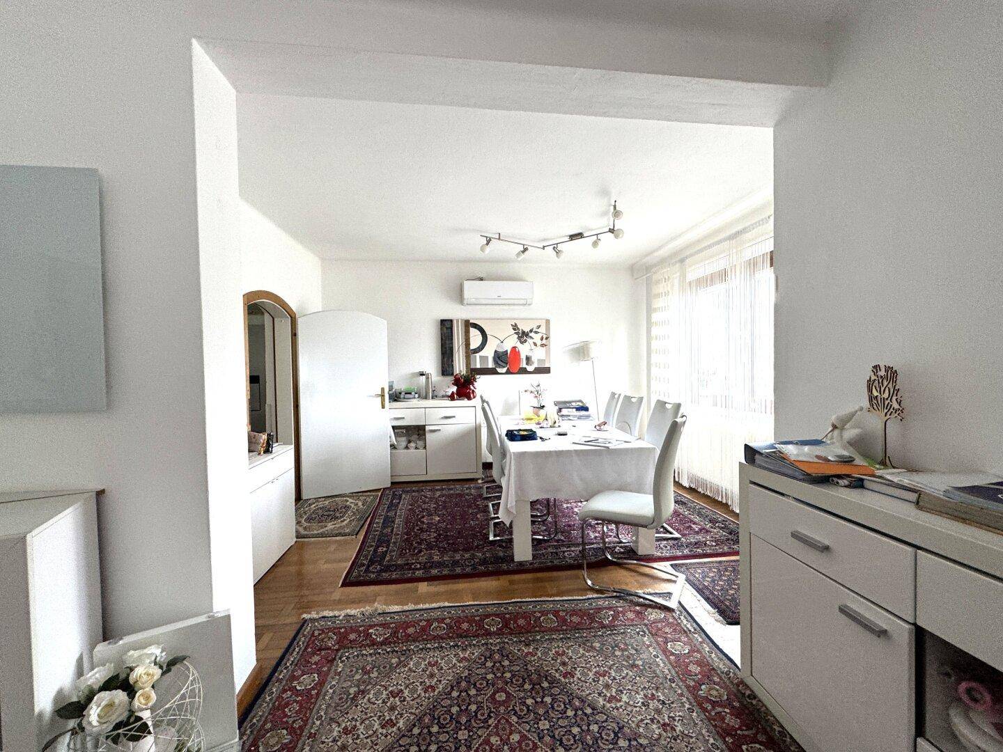 Offener Übergang vom Wohnbereich zum Esszimmer mit großem Esstisch und Klimaanlage.