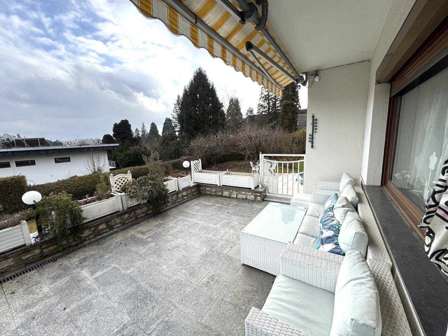 Geräumige Terrasse mit bequemen Loungemöbeln, Markise und Blick ins Grüne.