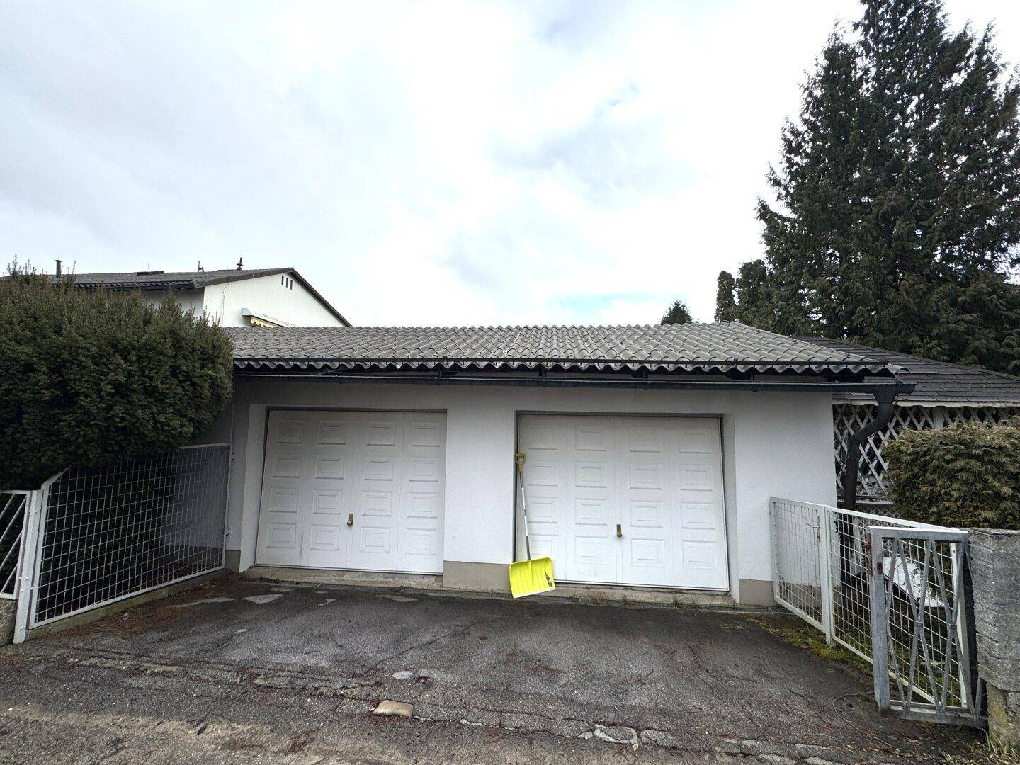 Doppelgarage mit zwei weißen Toren und einem gepflasterten Vorplatz.