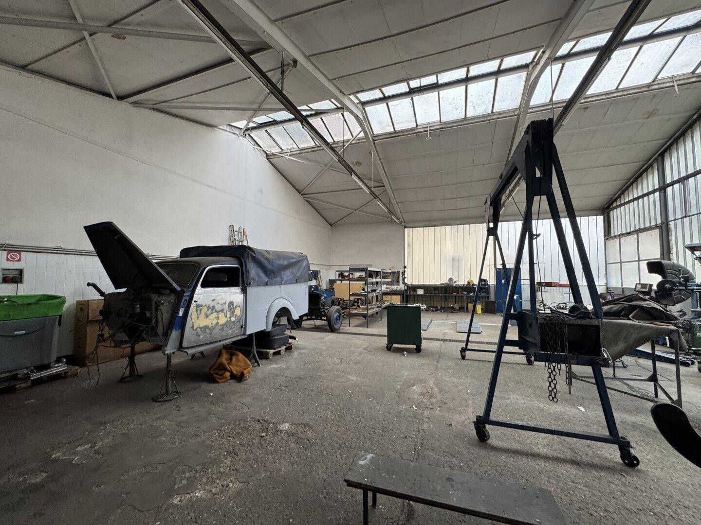 Große Werkstatthalle mit viel Platz und einem Oldtimer in Bearbeitung.