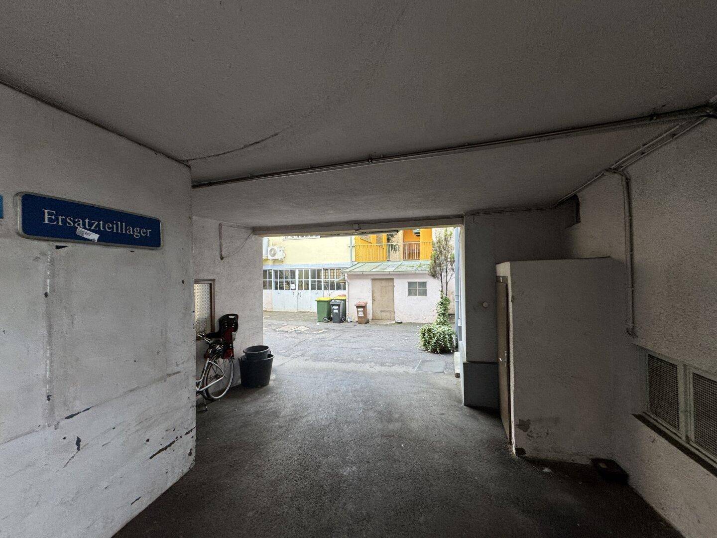 Zufahrt zum Innenhof mit Durchgang und Hinweisschild für Ersatzteillager.