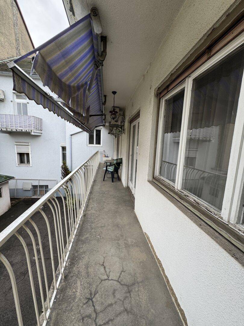 Langer Balkon mit Markise und Blick auf den Innenhofbereich.