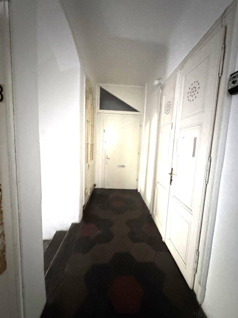 Flur mit dunklem, gemustertem Fliesenboden und weißen Türen.