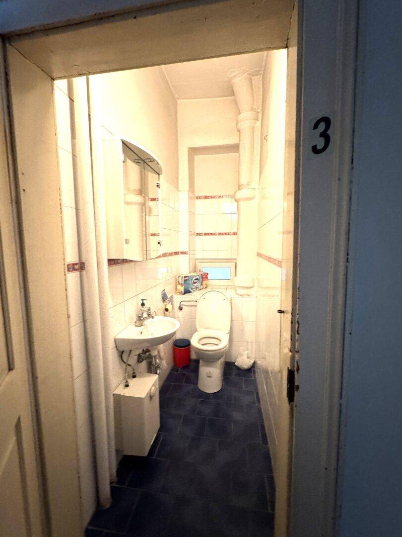 Kleines Badezimmer mit Waschbecken, Toilette und weißen Fliesen.