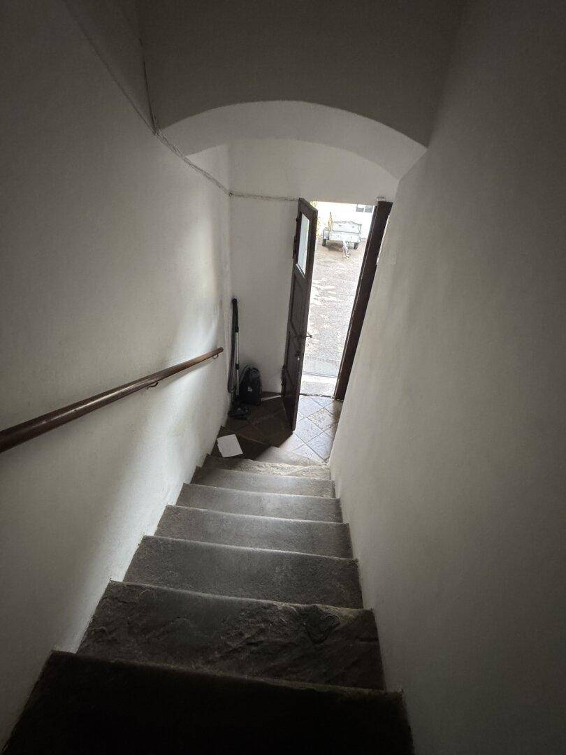Treppenhaus mit Steinstufen und Handlauf, führt in den unteren Bereich.