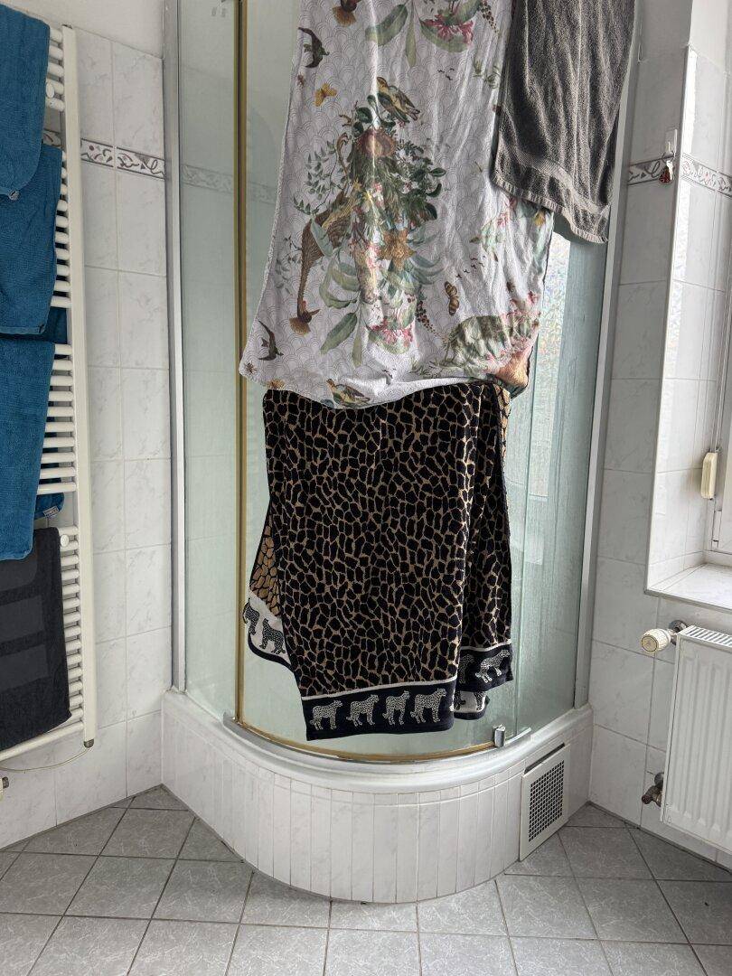 Badezimmer mit Duschkabine, weißen Fliesen und Handtuchheizkörper.