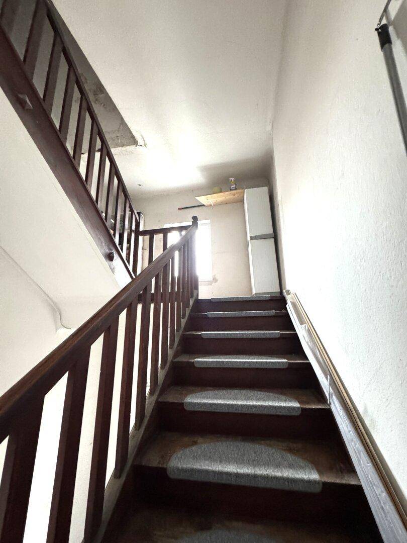 Holztreppe mit Geländer führt in die obere Etage.