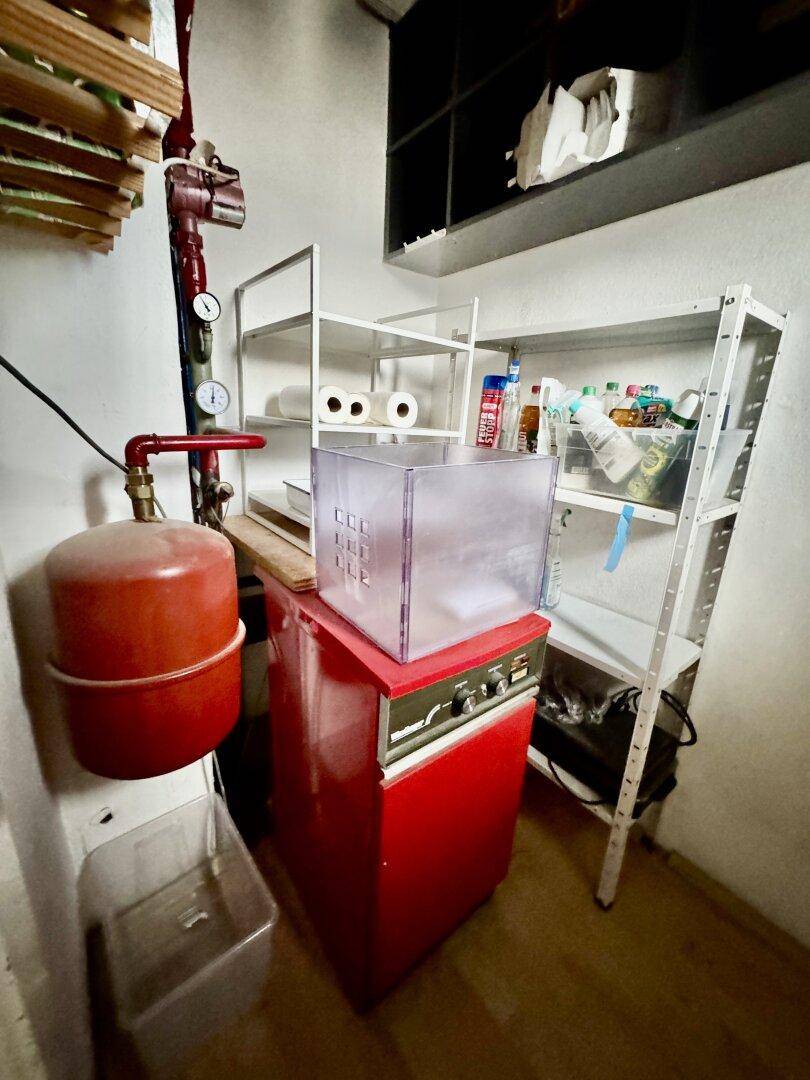 Heizungsraum mit rotem Boiler und Regalen für Lagerung.