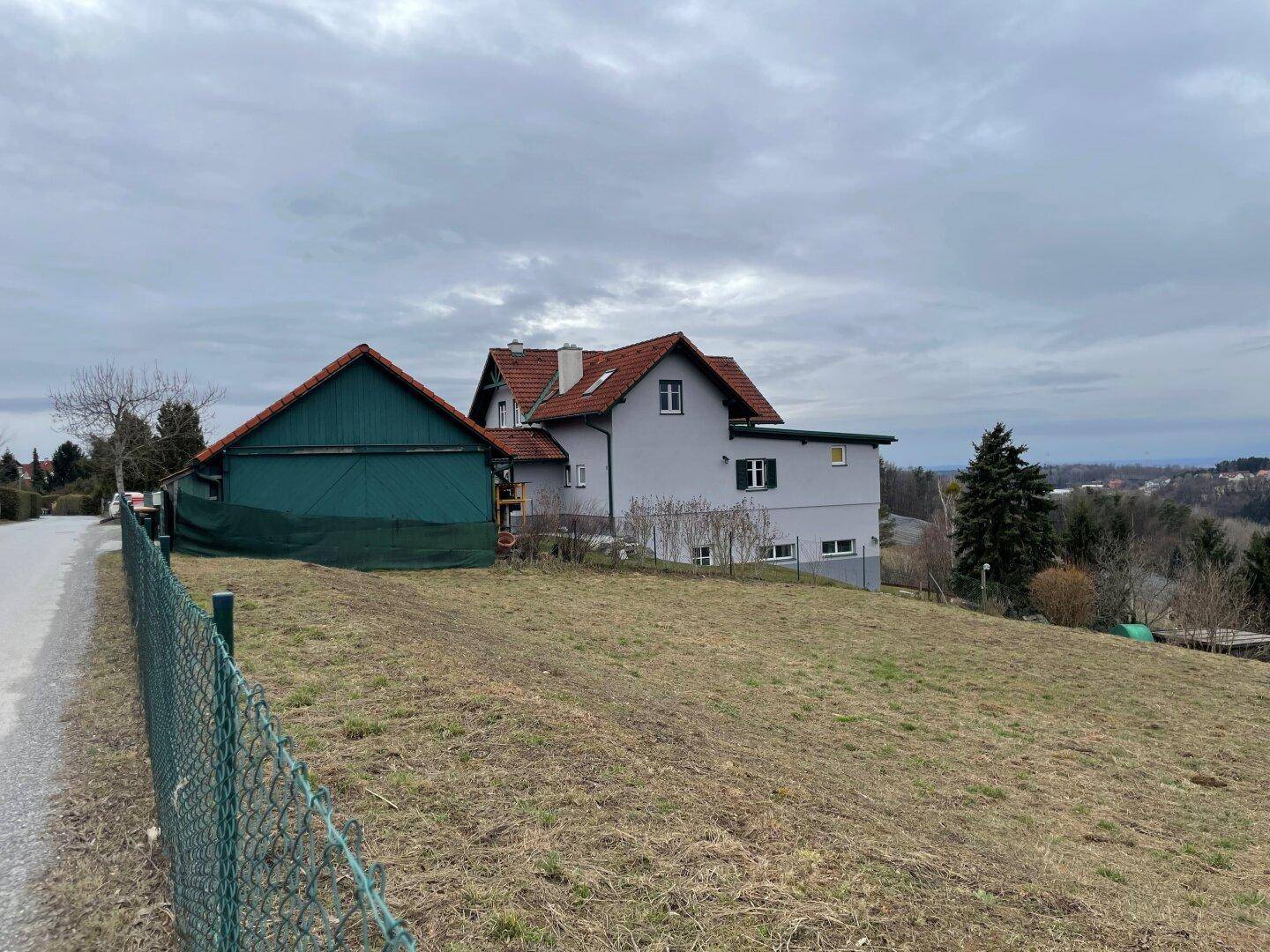 Haus in ländlicher Umgebung mit angrenzendem Feld und weitem Blick in die hügelige Landschaft.