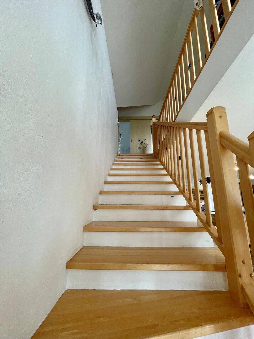 Helle Holztreppe mit Geländer, die in die obere Etage führt.