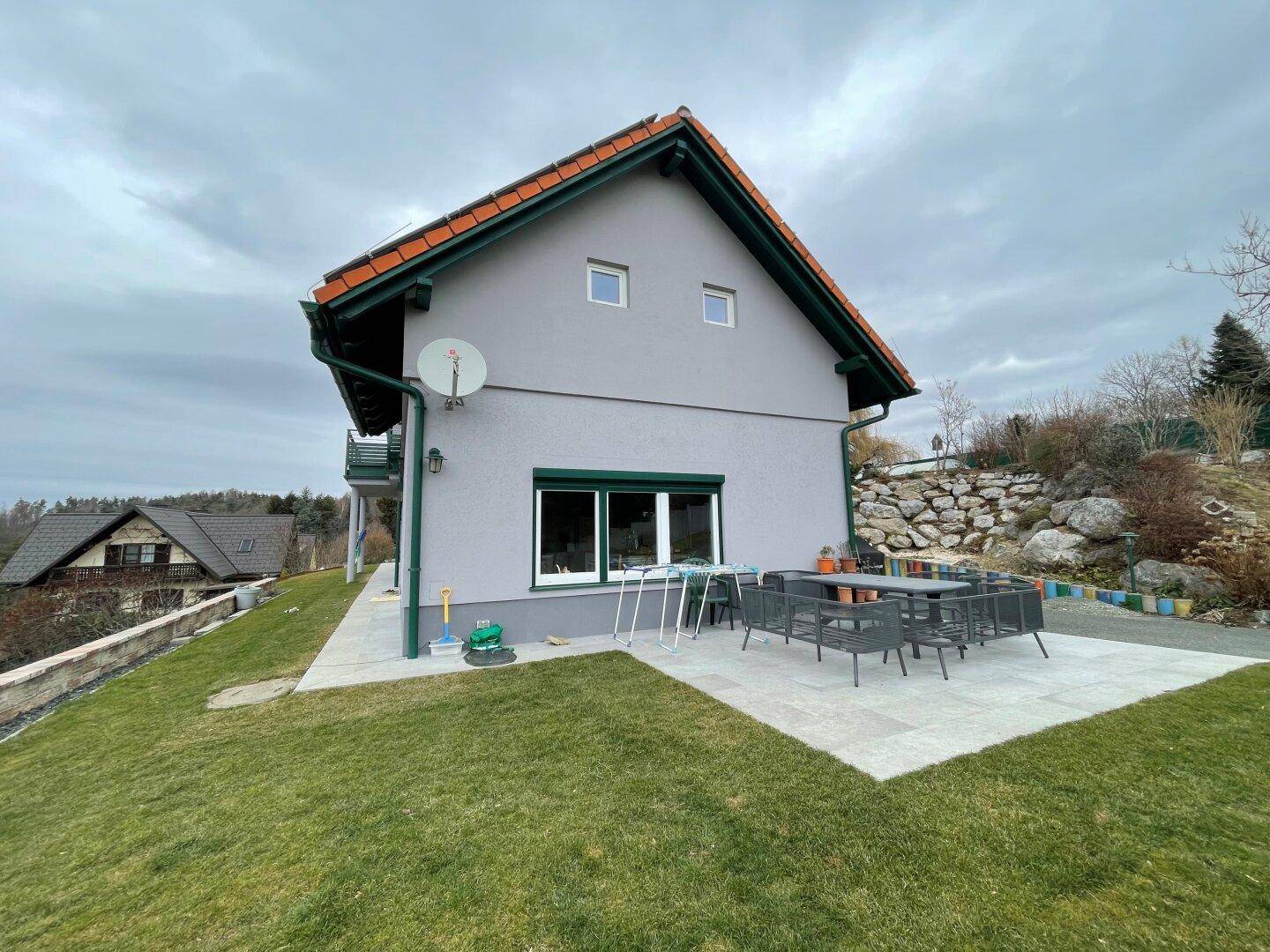 Große Terrasse mit modernen Gartenmöbeln und Blick auf die umliegende Landschaft und Felsen.