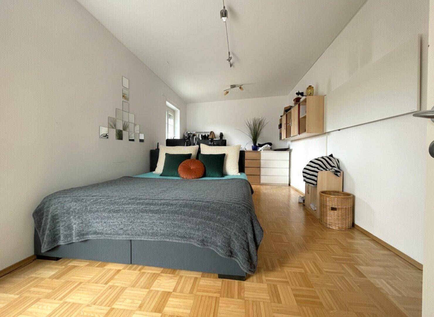 Modernes Schlafzimmer mit Parkettboden, Doppelbett und schlichten Möbeln.