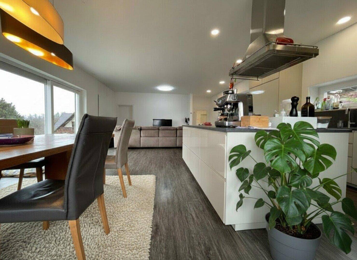 Offener Wohn-Essbereich mit moderner Küche, Kochinsel und Blick ins Wohnzimmer.