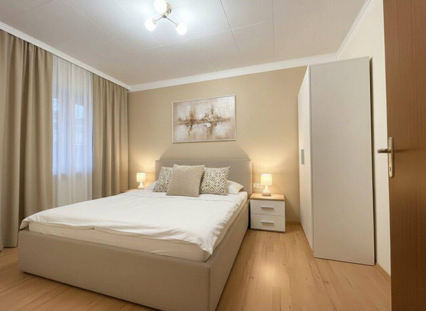Modernes Schlafzimmer mit Doppelbett, Nachttischen und hellem Parkettboden.
