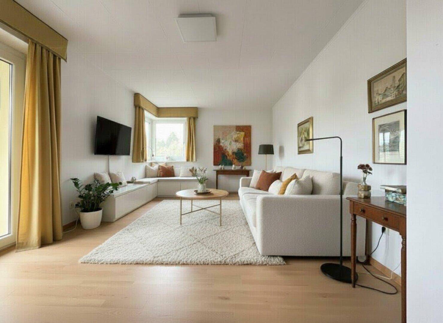 Helles Wohnzimmer mit Parkettboden, beigem Sofa und einem gemütlichen Fensterbereich.