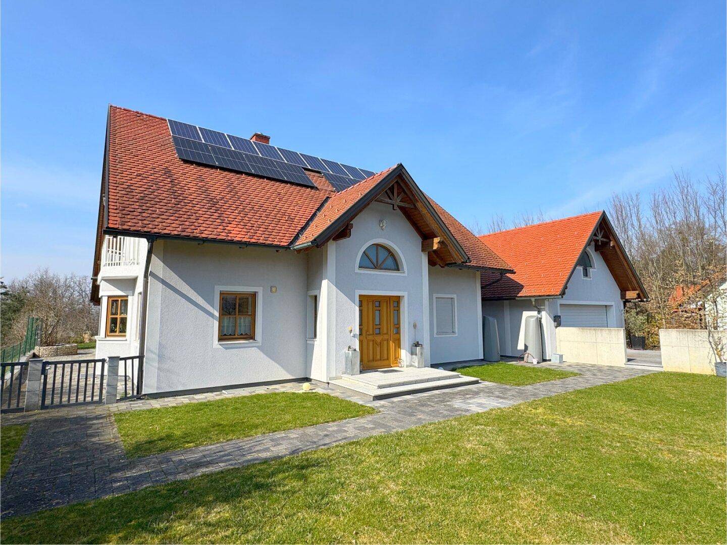 Frontansicht des gepflegten Einfamilienhauses mit Photovoltaikanlage auf dem Dach und grünem Vorgarten.