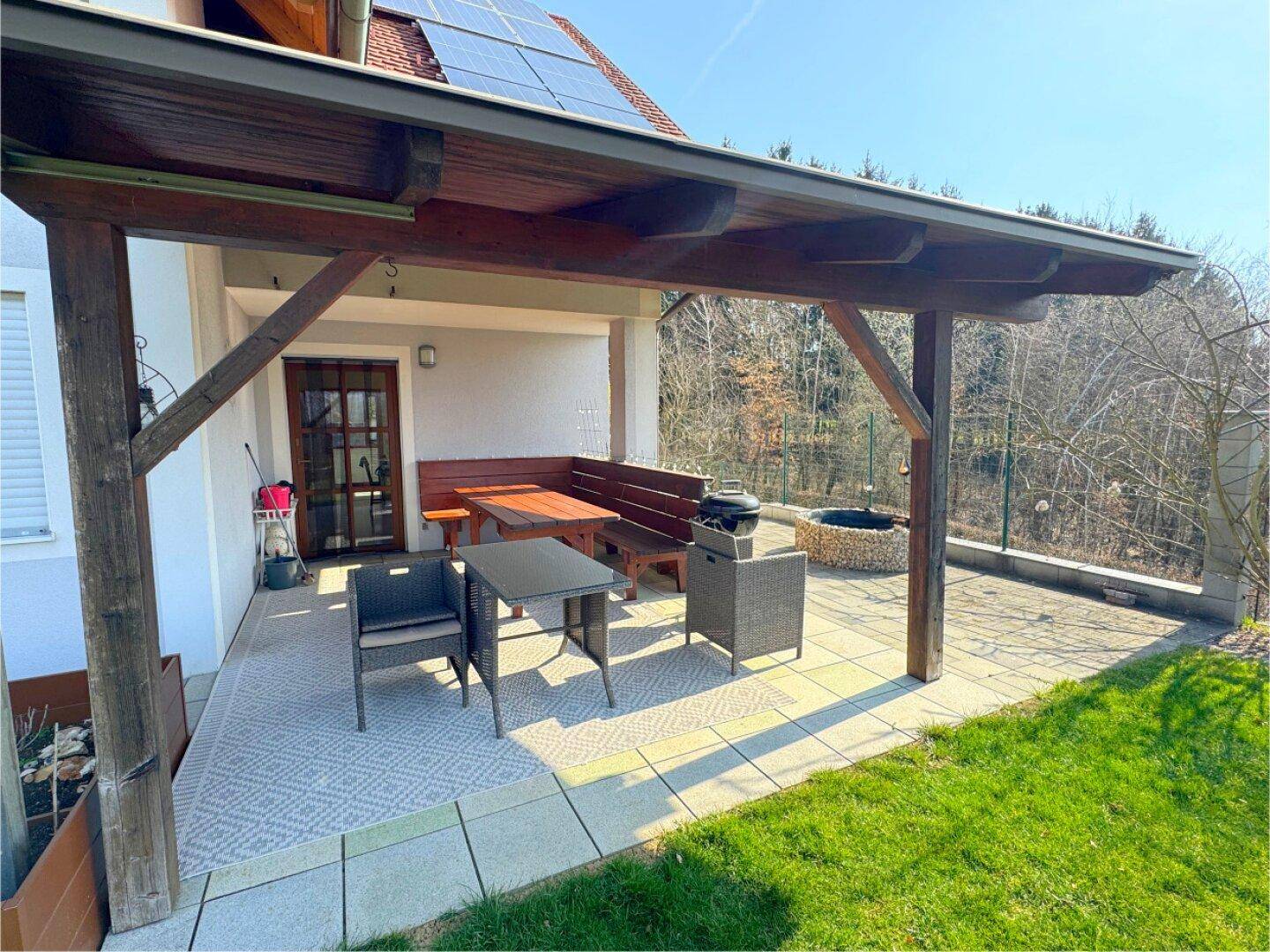 Gemütliche überdachte Terrasse mit Sitzgelegenheiten und Blick auf den weitläufigen Gartenbereich.
