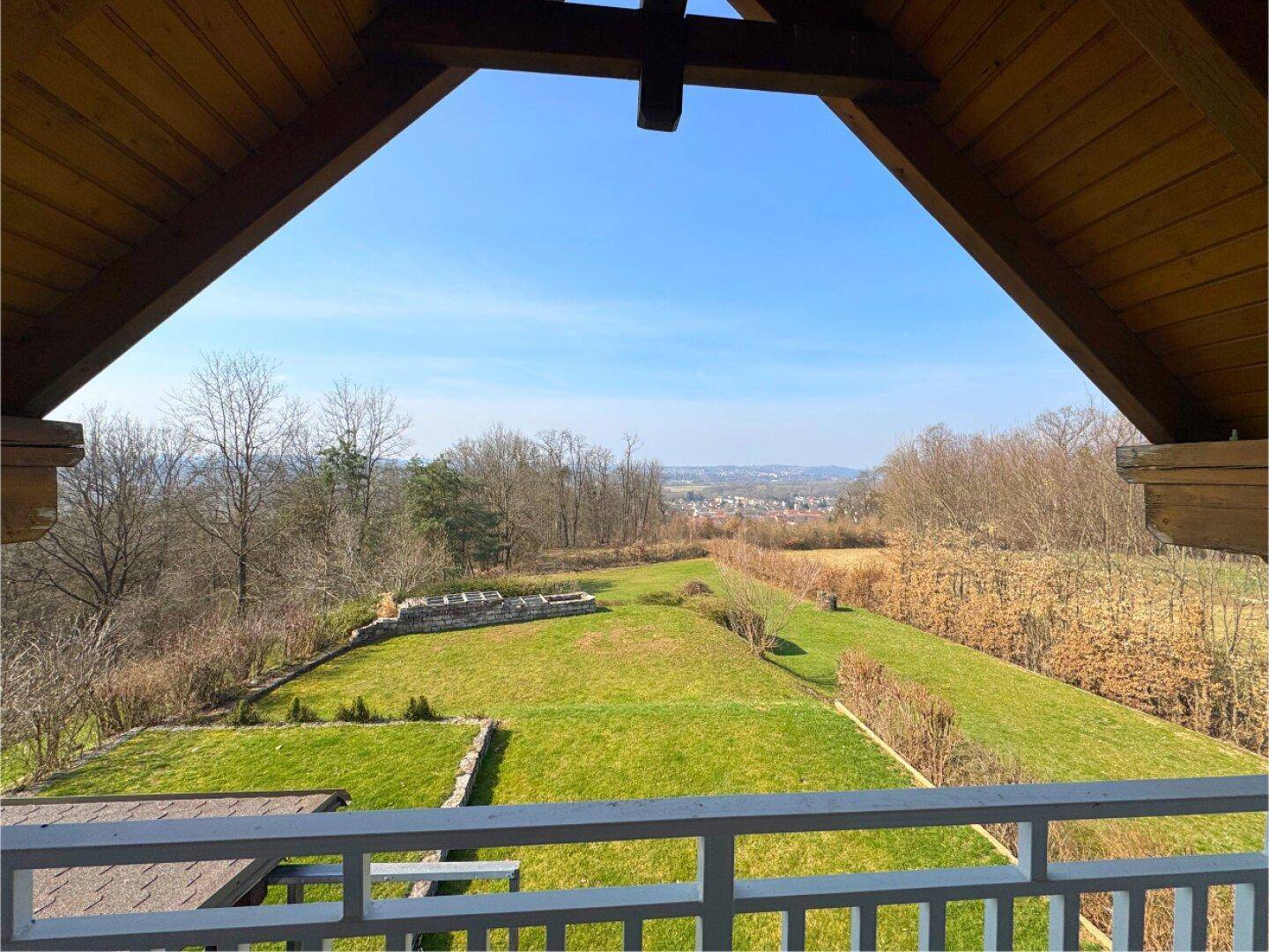 Blick vom Balkon über den weitläufigen Garten und die malerische Landschaft in der Ferne.