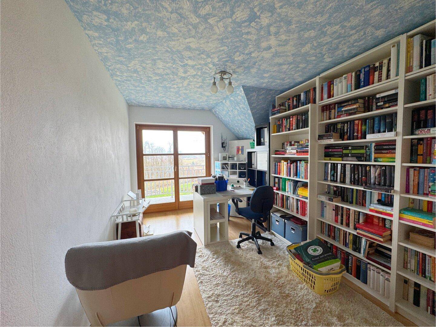 Geräumiges Arbeitszimmer mit großen Bücherregalen, Schreibtisch und Zugang zum Balkon.