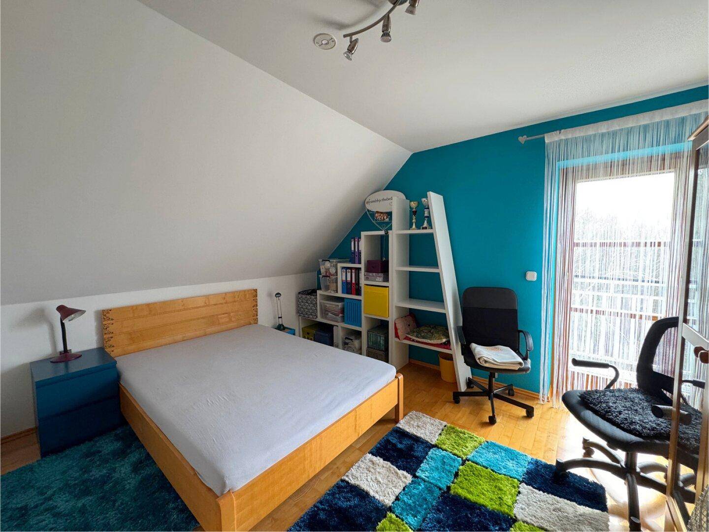 Farbenfrohes Kinderzimmer mit Bett, Schreibtisch und Zugang zum Balkon.