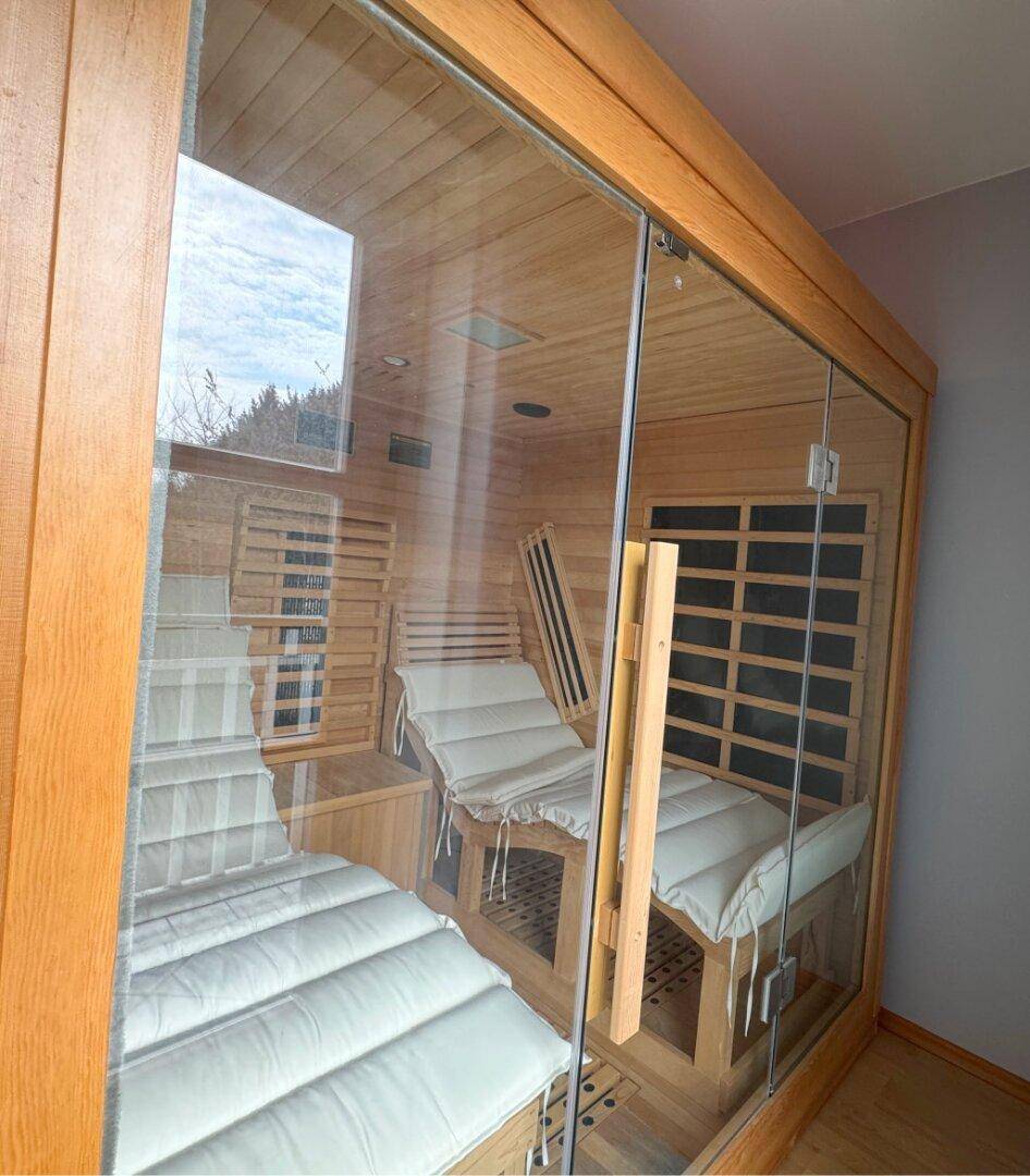 Moderne Sauna mit Holzbänken und Glasfront für entspannende Momente.