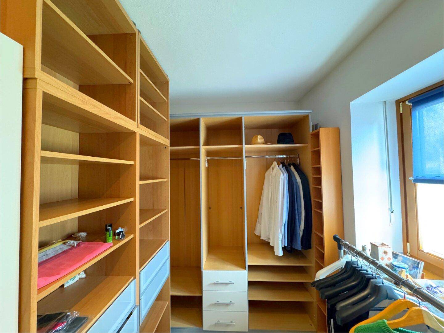 Geräumiger begehbarer Kleiderschrank mit vielen Regalen und Hängemöglichkeiten.