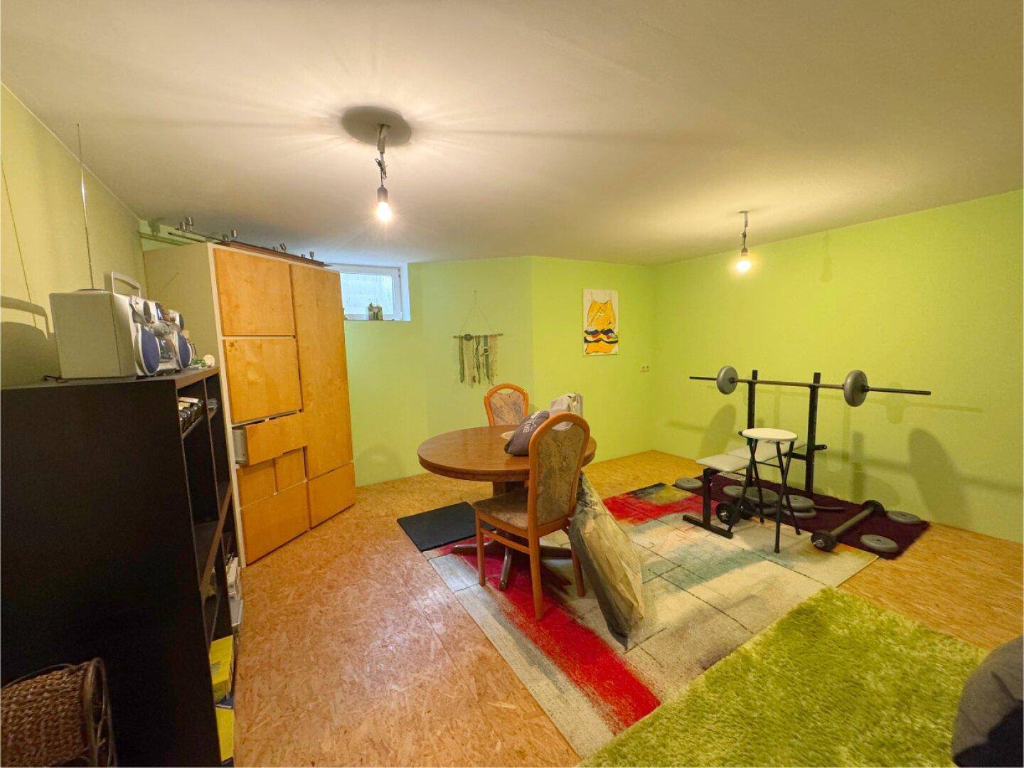 Vielseitiger Kellerraum, eingerichtet als Fitness- und Hobbybereich mit Tisch und Gewichten.