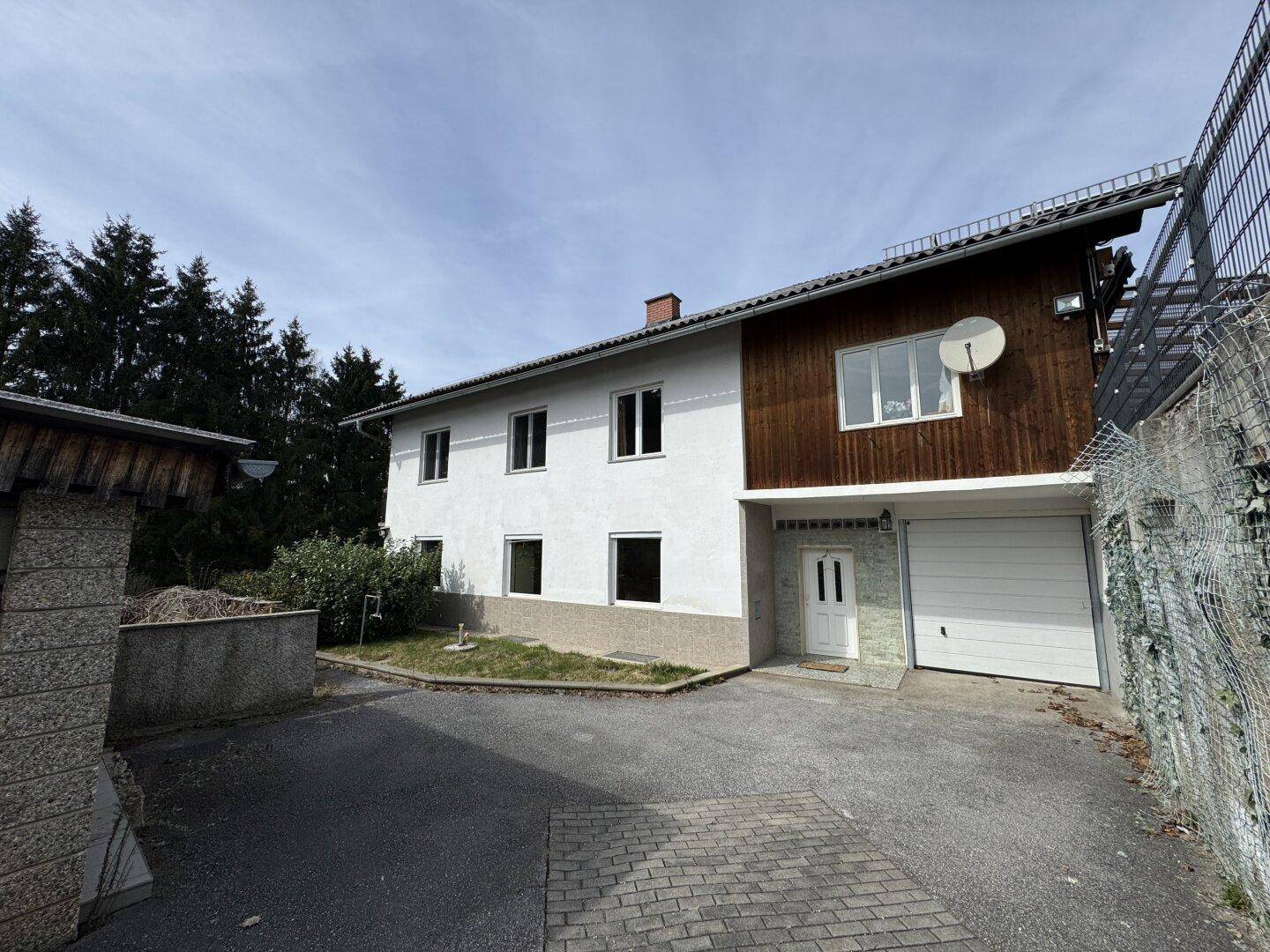 Vorderansicht des Hauses mit integrierter Garage und Holzelementen an der Fassade und Zufahrt.