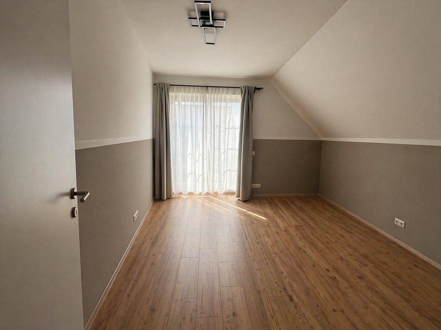 Helles Schlafzimmer im Dachgeschoss mit Laminatboden und schrägen Wänden.