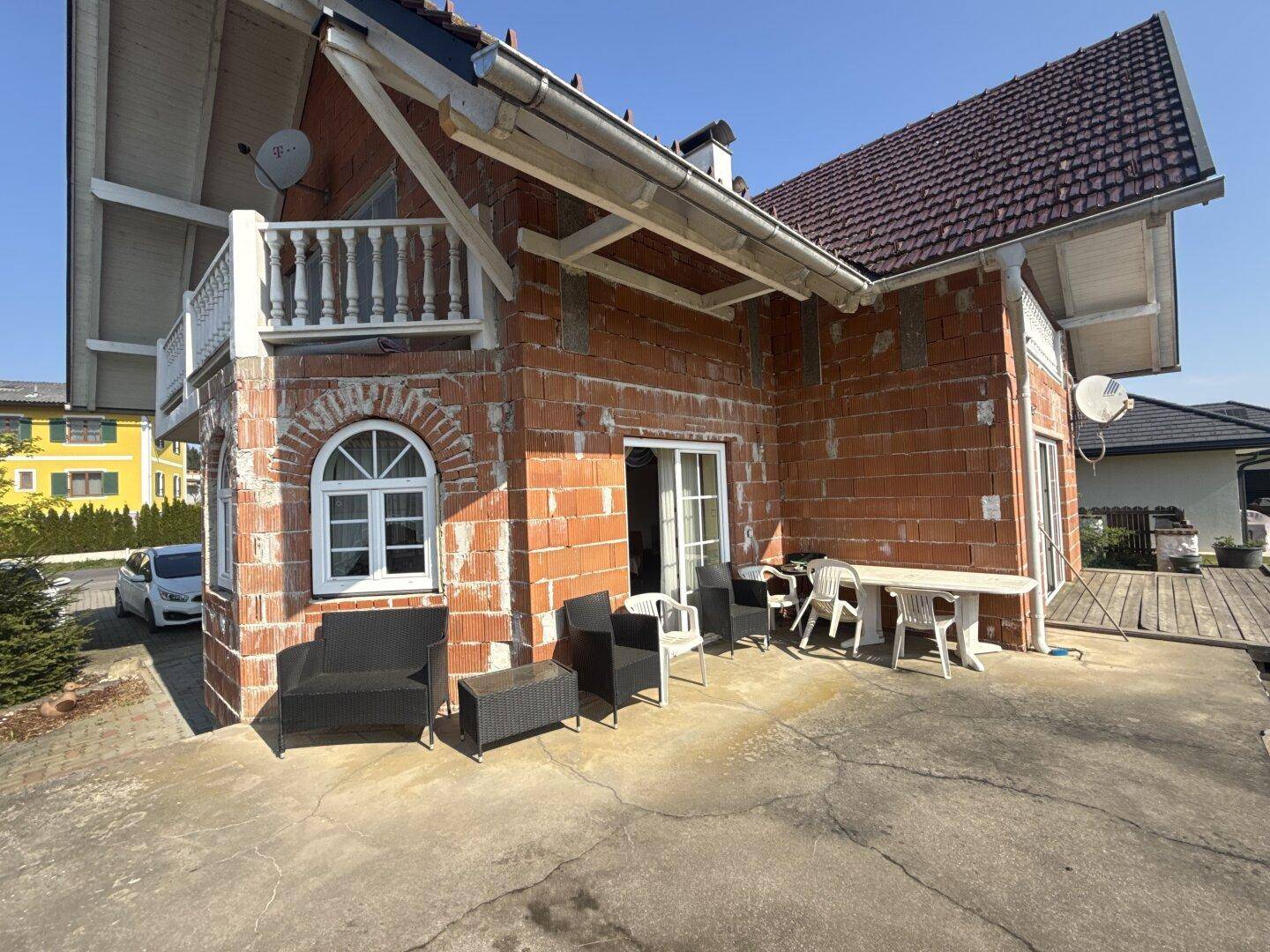 Große Terrasse mit Gartenmöbeln und Zugang zum Haus, teilweise noch im Rohbau.