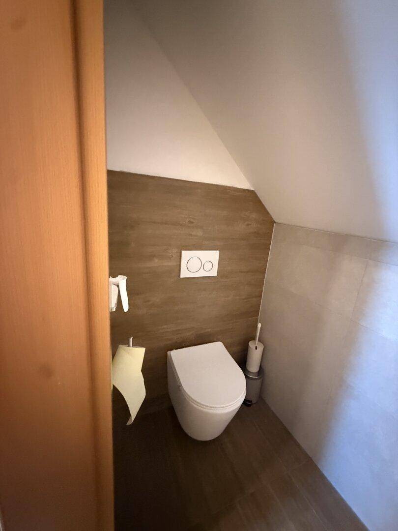 Kleines WC im Dachgeschoss mit modernen Fliesen und wandhängender Toilette.