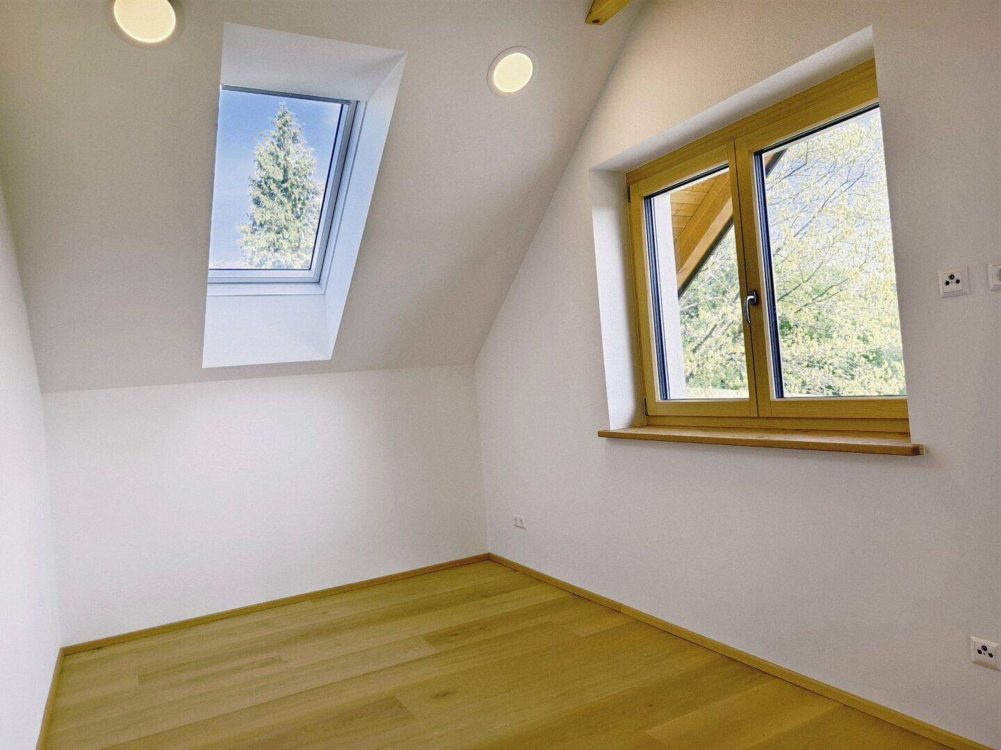 Helles Dachzimmer mit Holzboden, Dachfenster und Blick ins Grüne, ideal als Schlafzimmer.